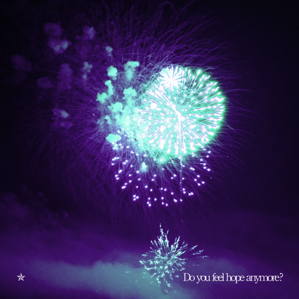 Bright cyan fireworks exploding in a dark purple sky.